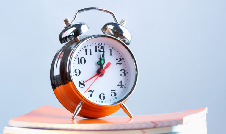 Stack of copybooks with alarm clock on its top