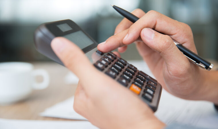 Close-up of male hands using calculator. Unrecognizable accountant holding pen when pushing button on calculator. Finance concept